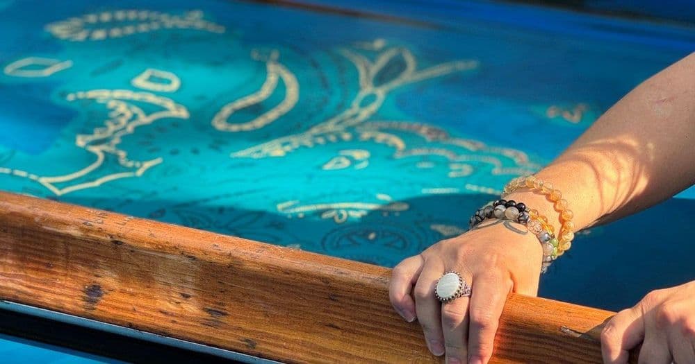 Hands pulling a squeegee across a screen-printing frame in a print workshop